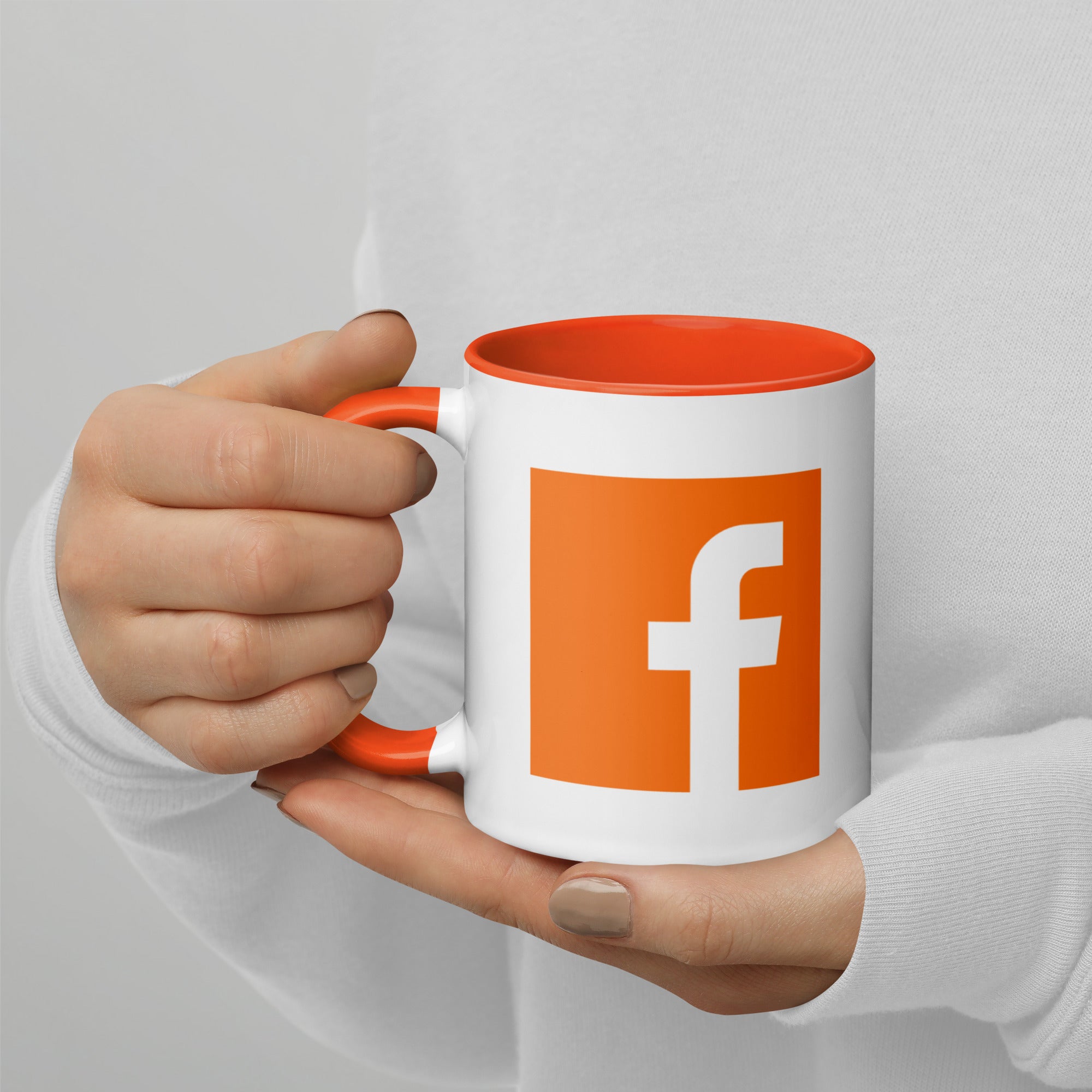 model holding an orange mug displaying an orange facebook logo