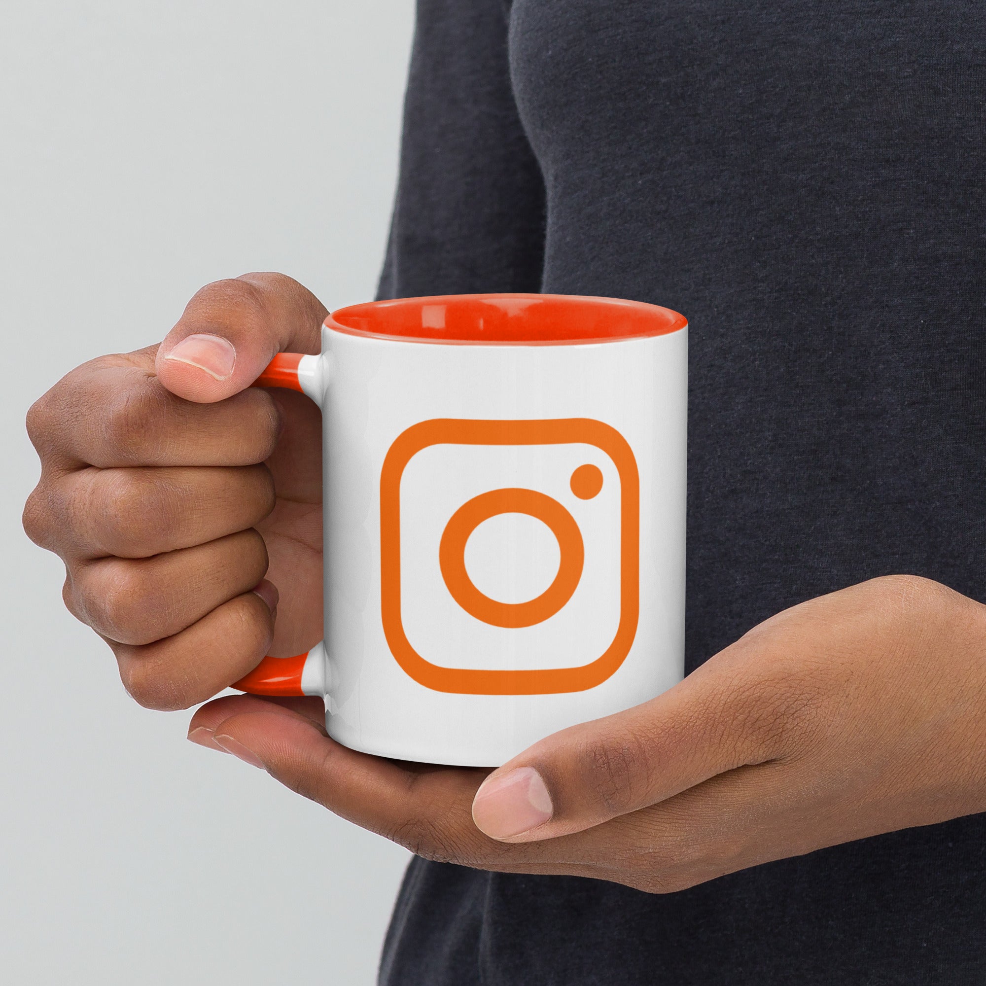 model holding an orange mug displaying an orange instagram logo